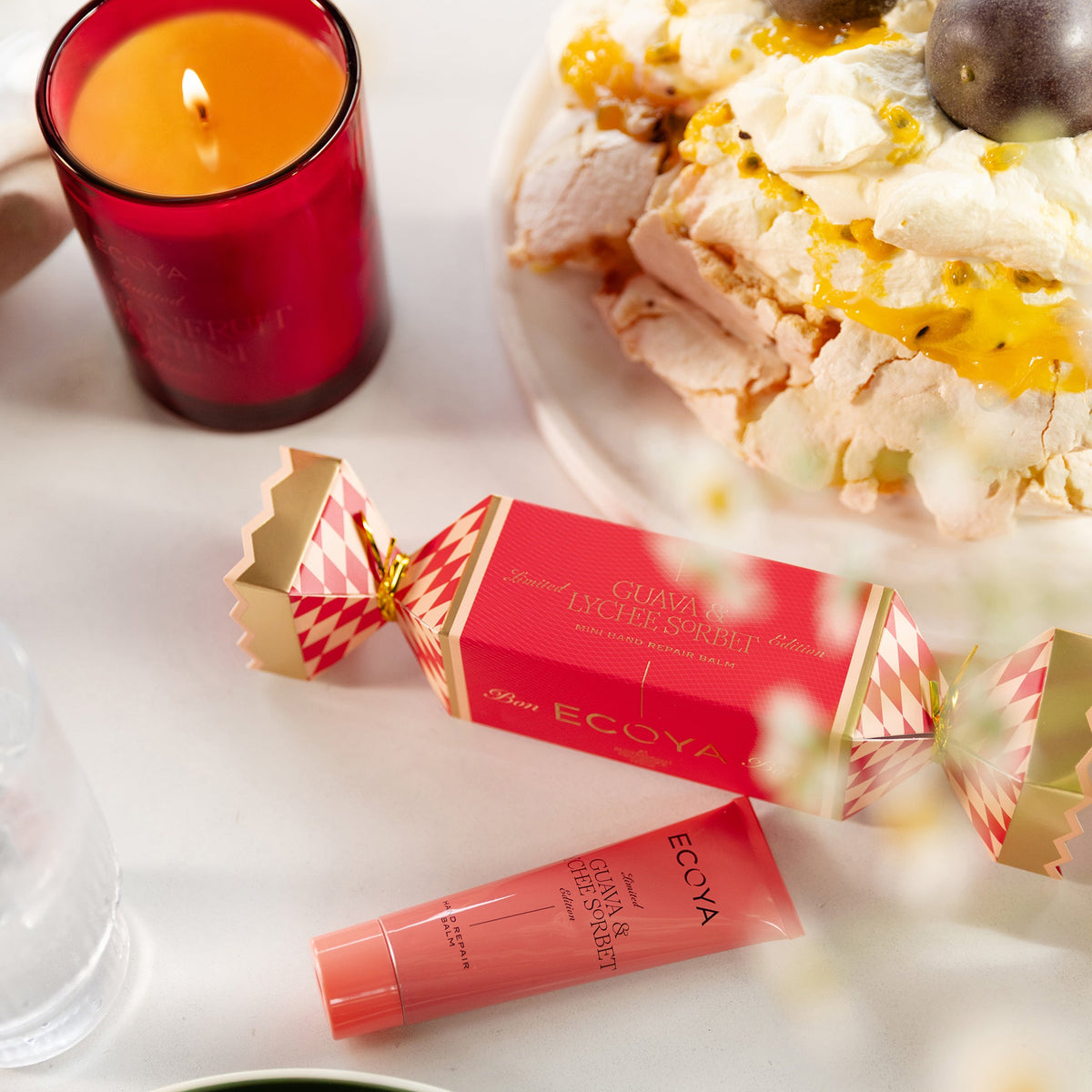 Ecoya Guava and Lychee Sorbet hand repair bonbon on a Christmas lunch table beside a pavlova and a lit candle